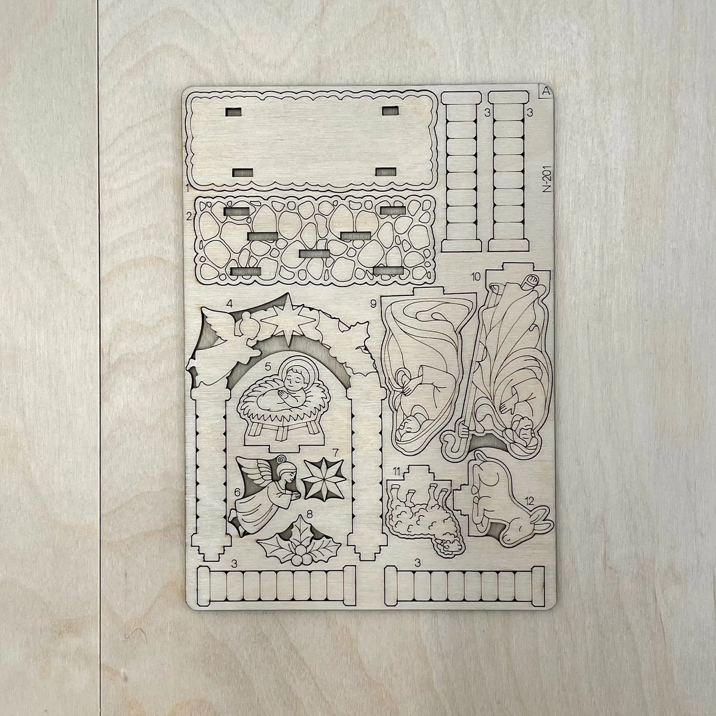 Decorative wooden template with Christmas-themed cutouts on a wooden surface