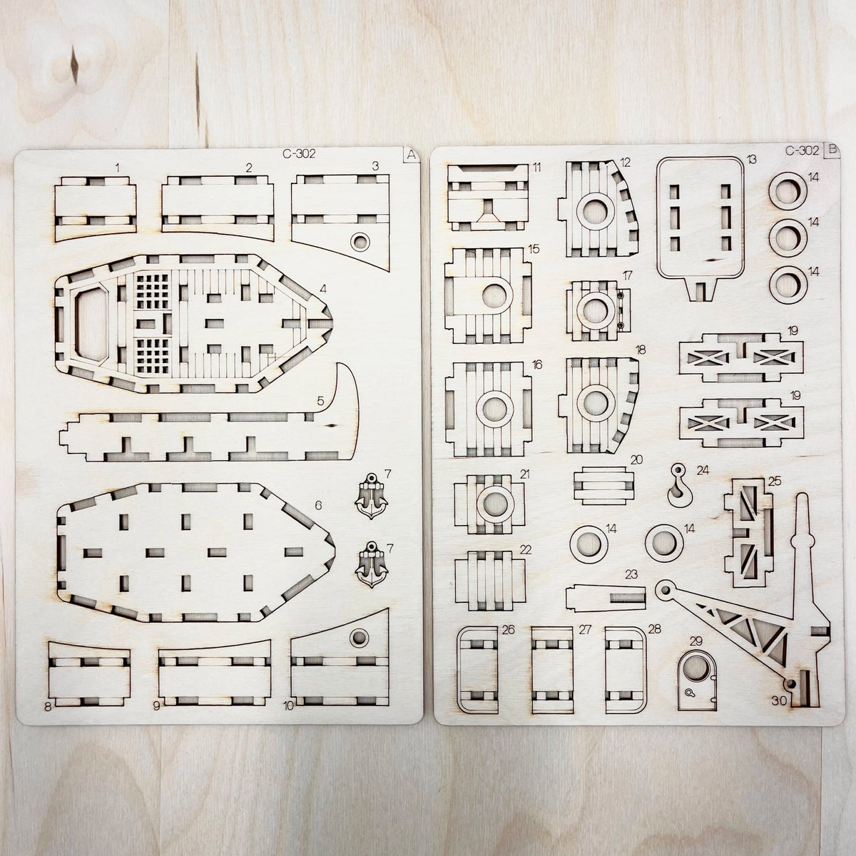 Set of laser-cut ship model parts on a wooden surface