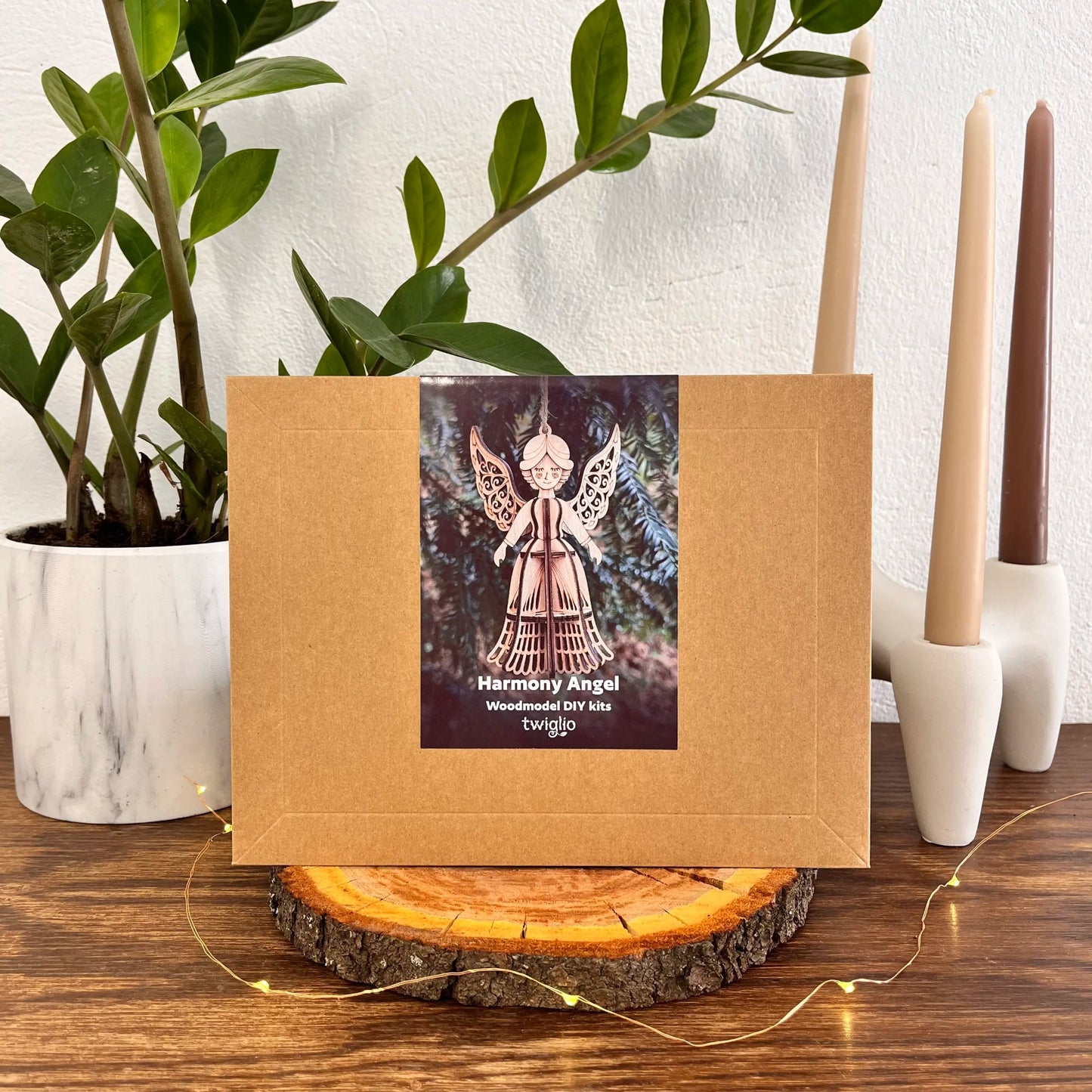 Brown box with a Harmony Angel product label on a wooden surface with plants and candles in the background