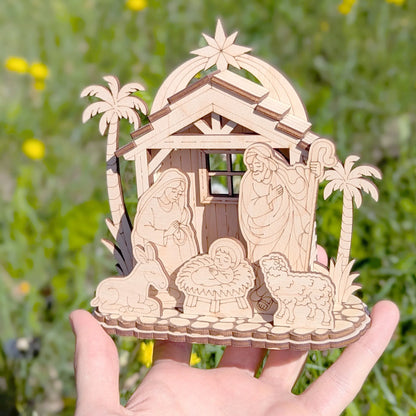 Wooden nativity scene model held in a hand with a blurred green background