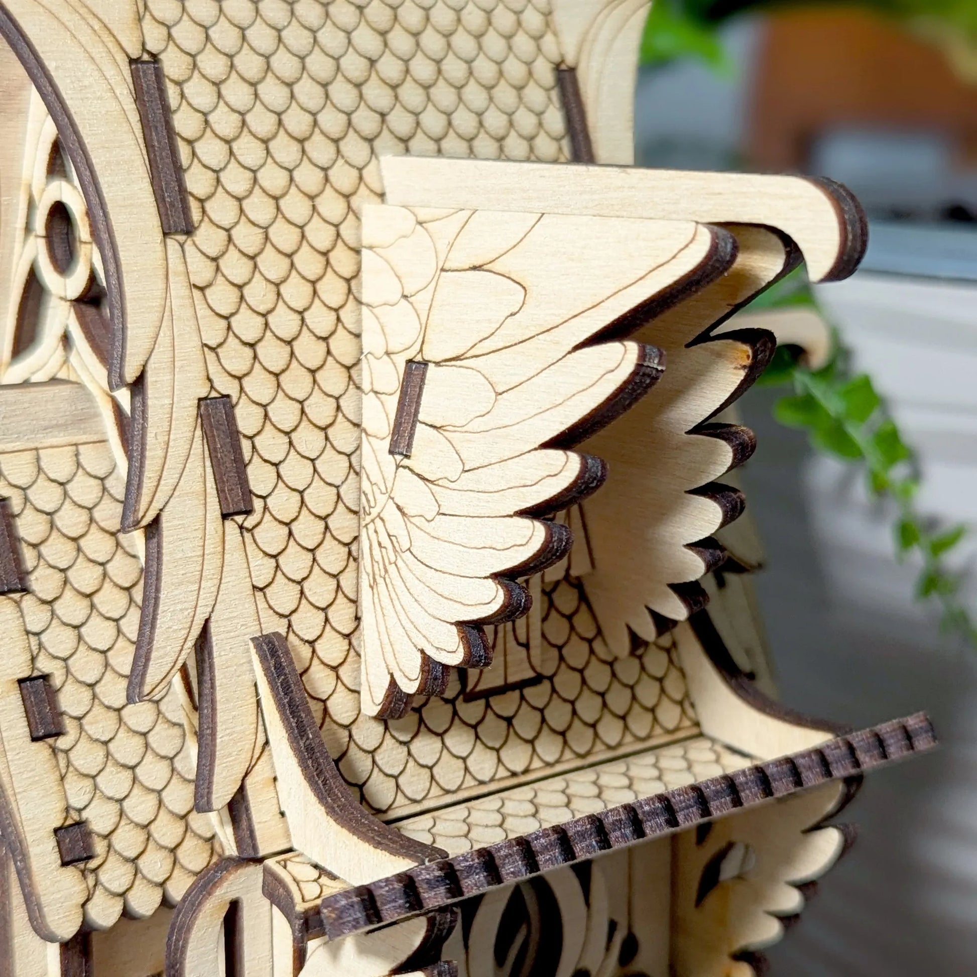 Wooden birdhouse model with detailed scales and wings on a blurred background