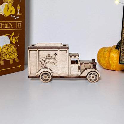 Wooden model of a truck on a white surface with a pumpkin and book in the background