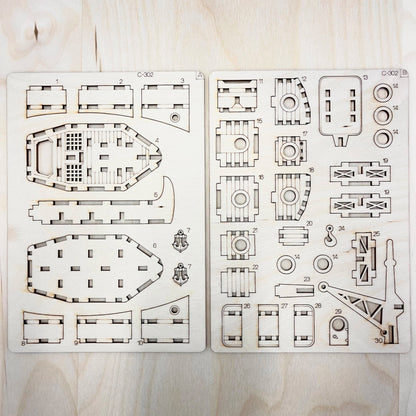 Set of laser-cut ship model parts on a wooden surface