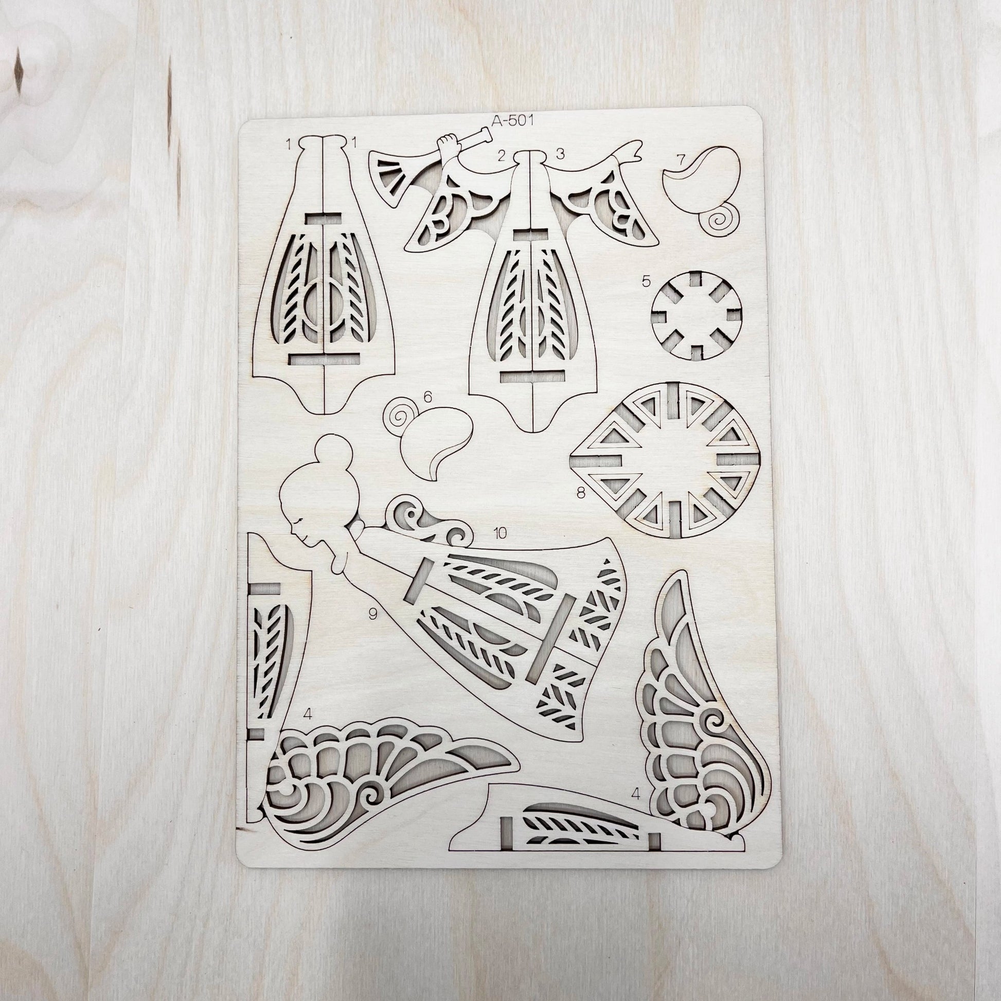 Set of laser-cut angel model parts on a wooden surface