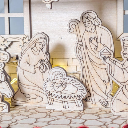 Wooden nativity scene with Mary, Joseph, and baby Jesus on a stone path.