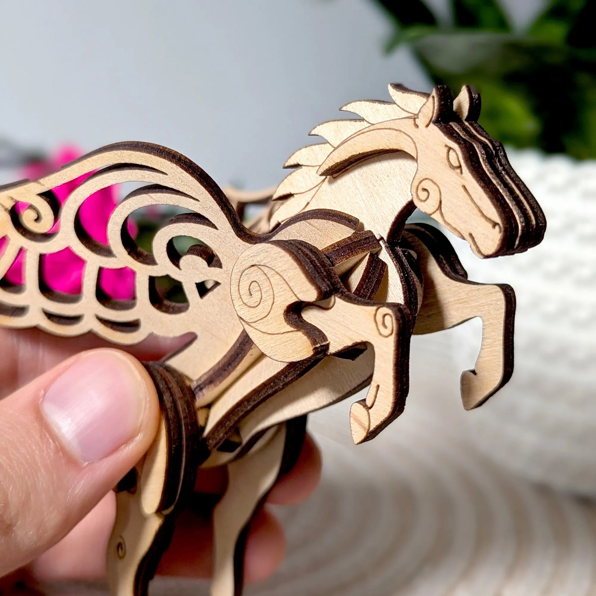 Wooden horse puzzle held by a hand with a blurred background