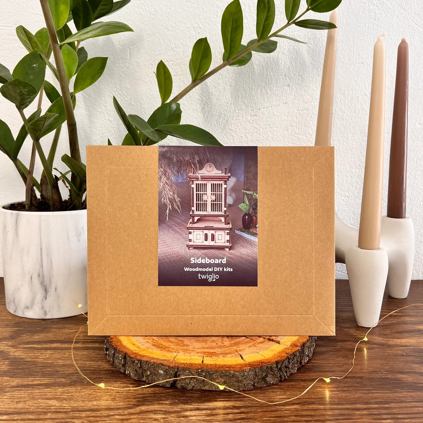 Wooden DIY kit packaging on a wooden surface with plants and candles in the background