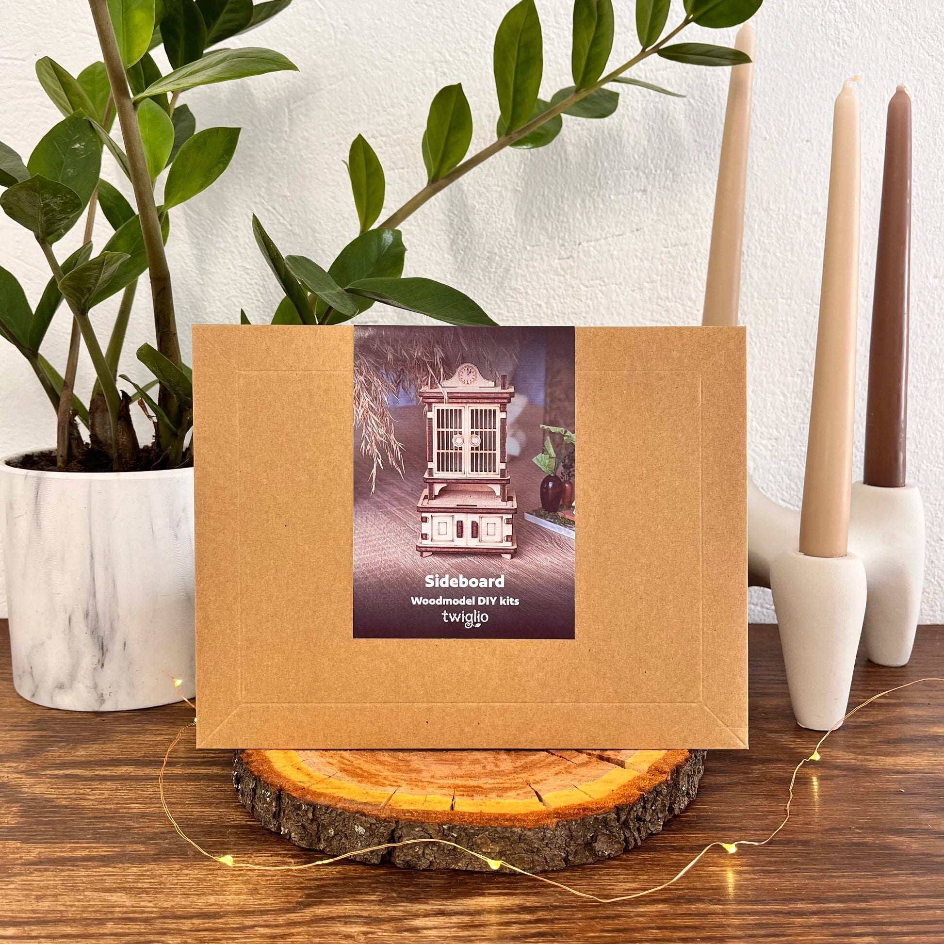 Wooden DIY kit packaging on a wooden surface with plants and candles in the background