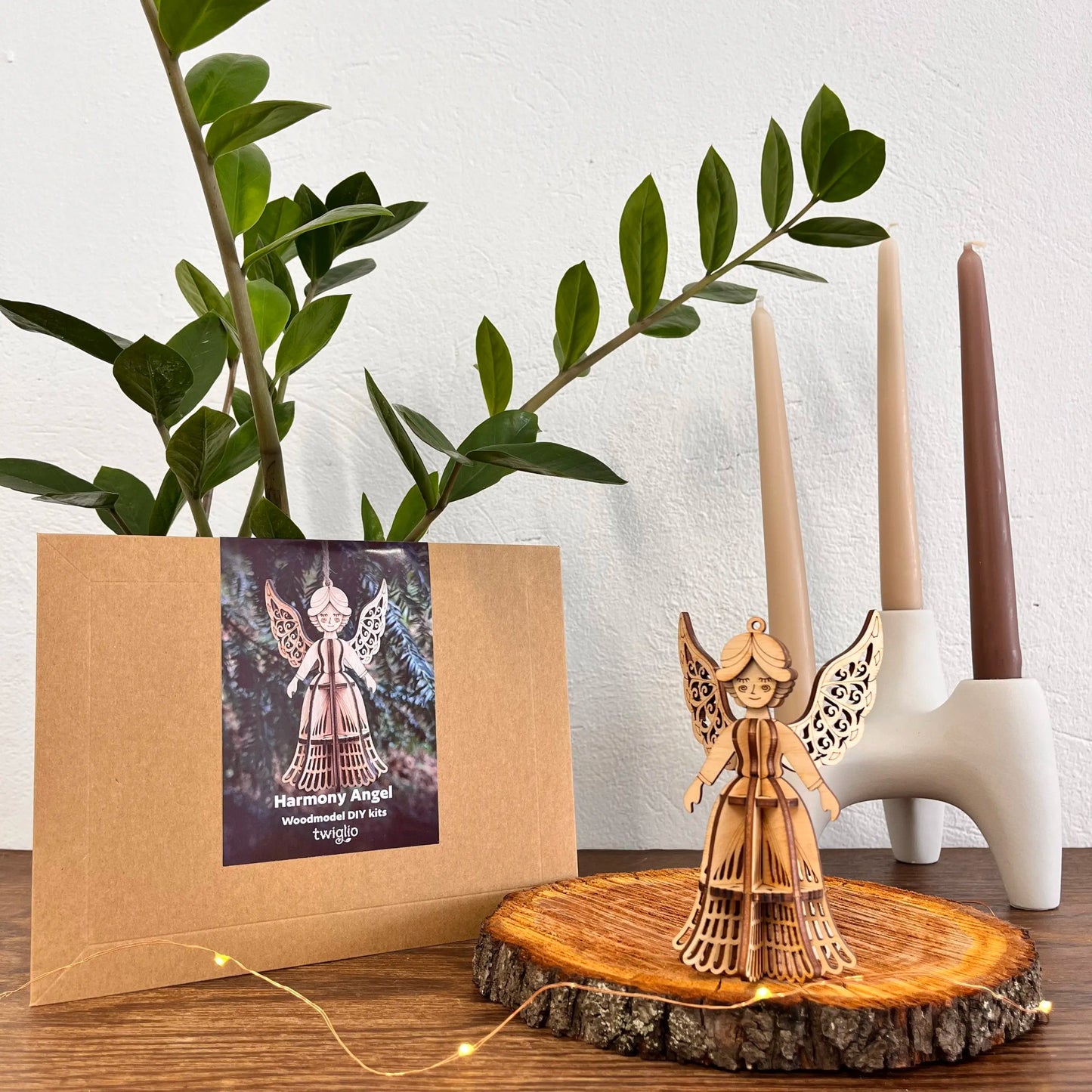 Wooden angel figurine on a wooden stand with a plant and candles in the background