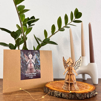 Wooden angel figurine on a wooden stand with a plant and candles in the background