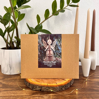 Brown box with a Harmony Angel product label on a wooden surface with plants and candles in the background