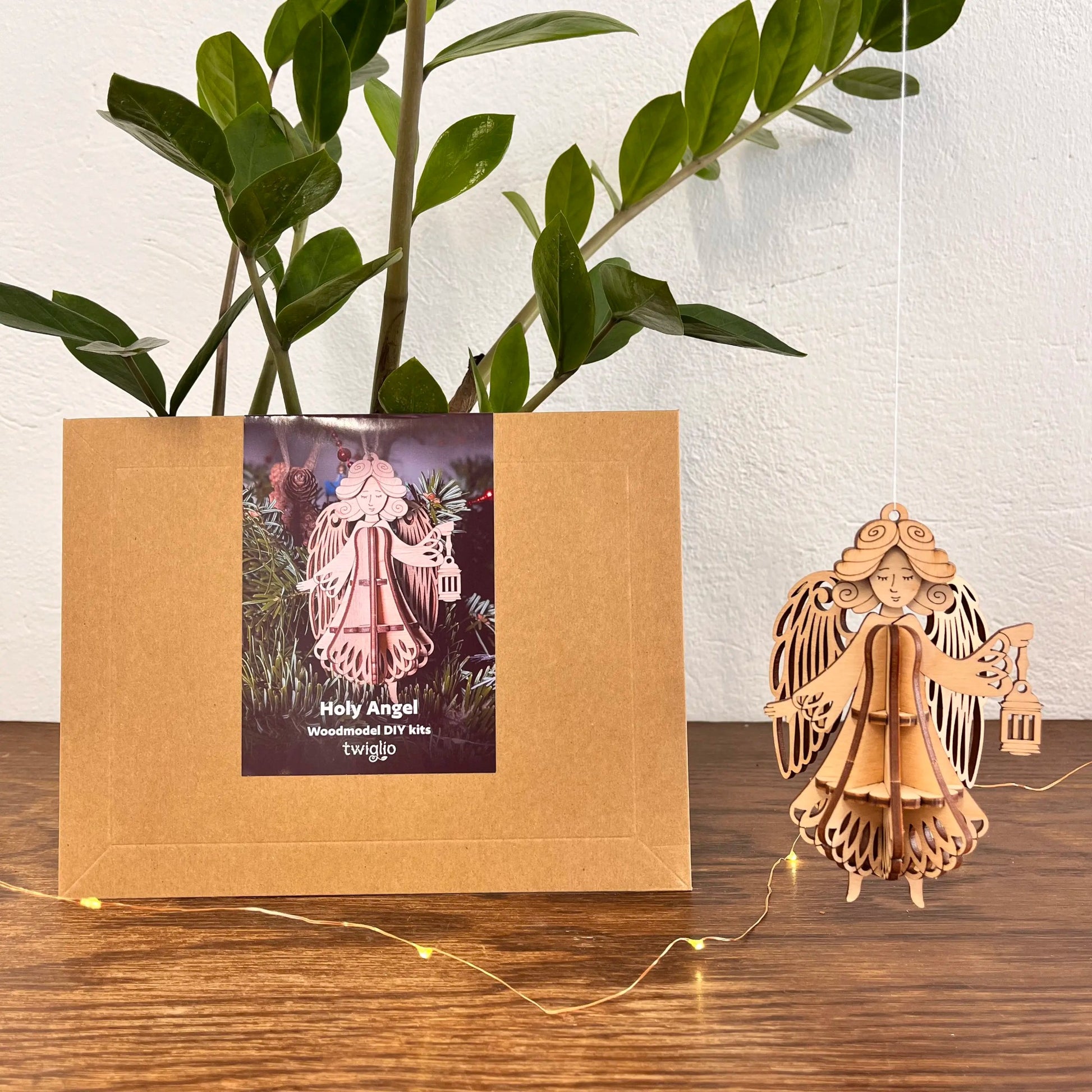 Wooden angel figurine next to a cardboard box with a product image on a wooden surface.