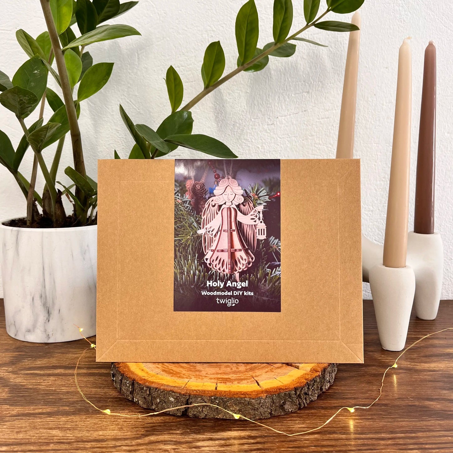 Kraft paper packaging with a decorative label featuring an angel figure on a wooden surface with candles and plants.