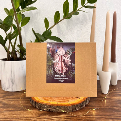 Kraft paper packaging with a decorative label featuring an angel figure on a wooden surface with candles and plants.