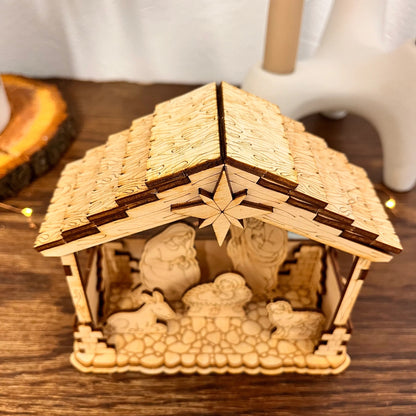 Wooden nativity scene set in a stable with straw roof on a wooden surface.