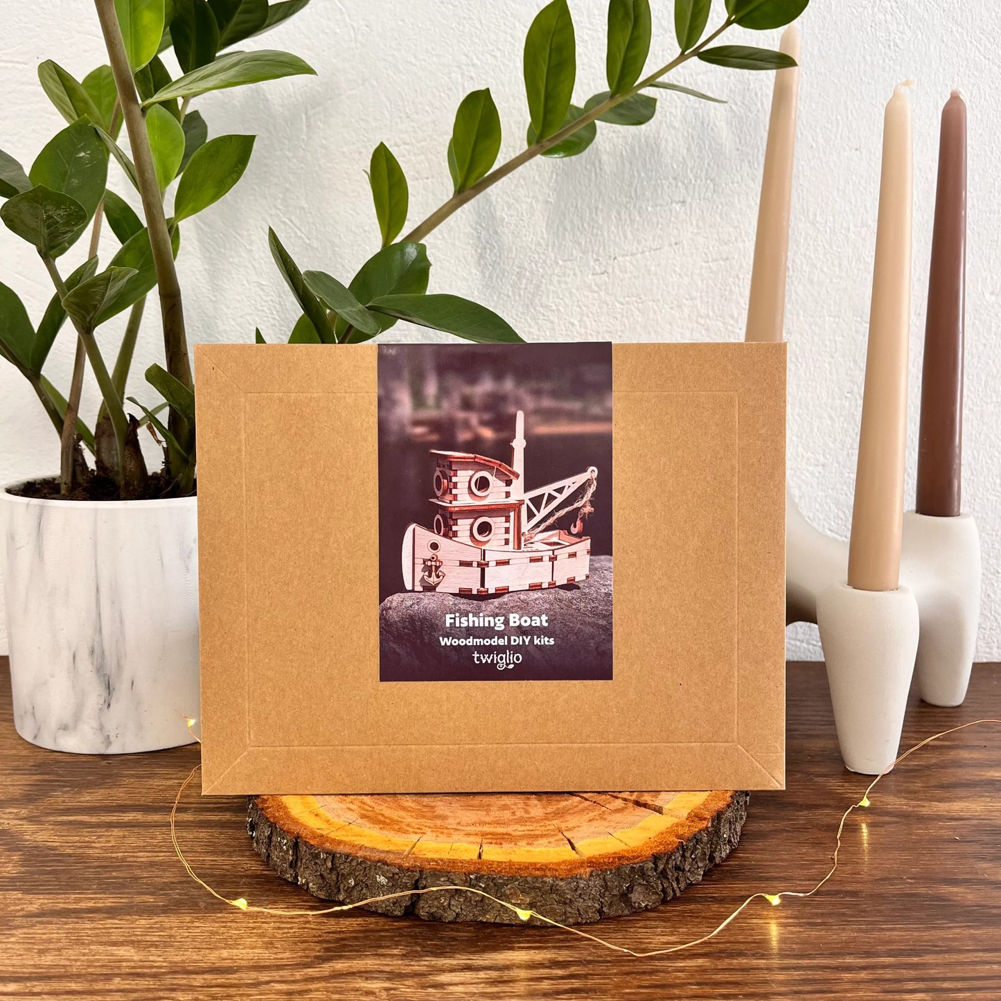Kraft paper packaging with a fishing boat illustration on a wooden surface with candles and a plant.