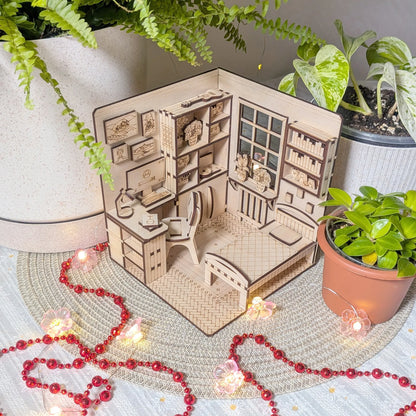 Wooden model of a miniature room with furniture and decor, surrounded by potted plants and string lights.