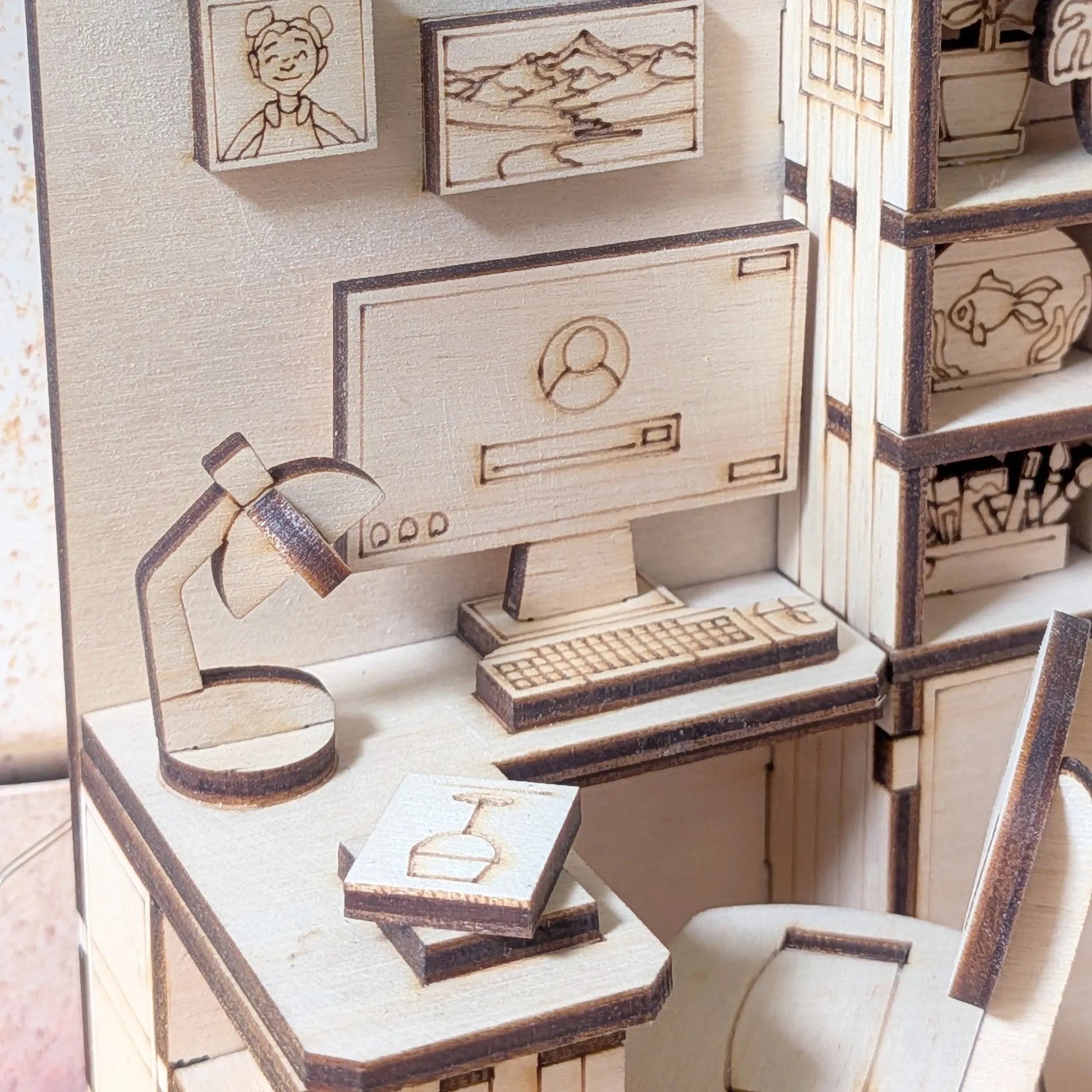 Wooden model of a desk setup with computer, chair, and accessories on a white background