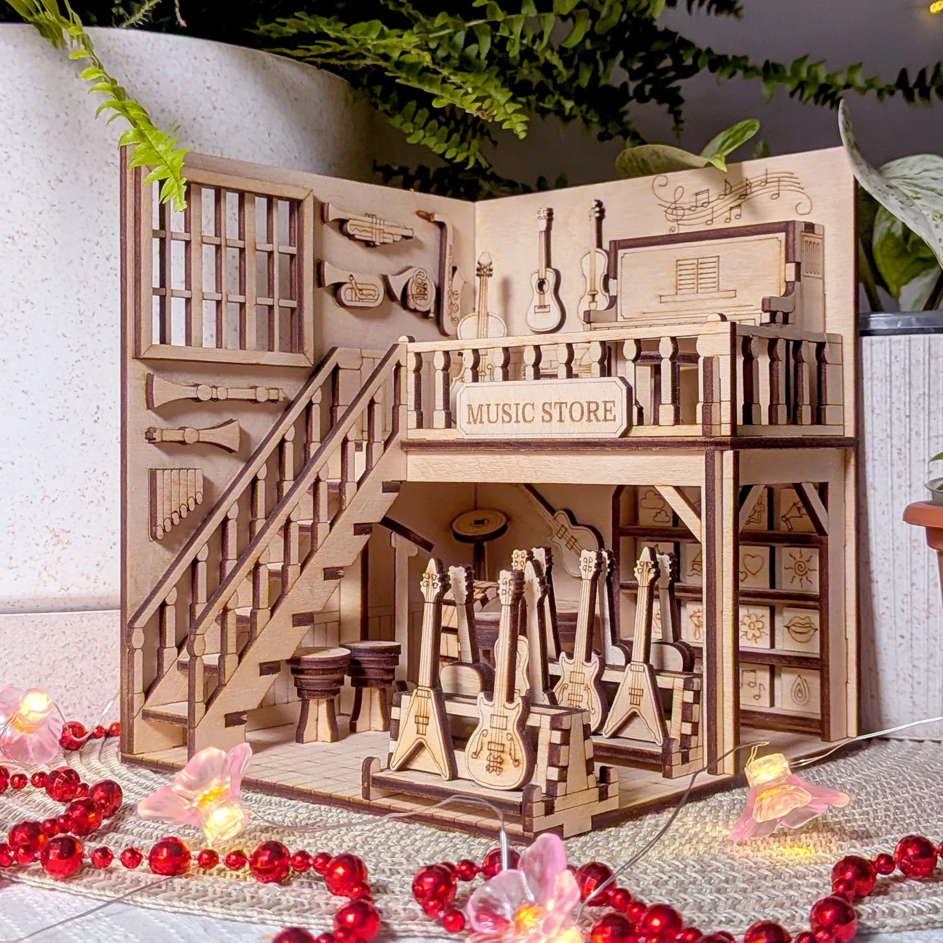 Wooden model of a music store with guitars and shelves, surrounded by decorative elements.
