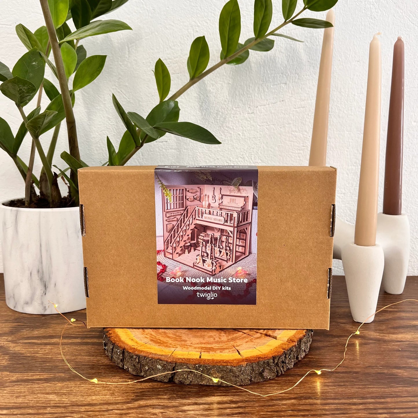 Brown box with a label on a wooden surface with candles and a plant in the background