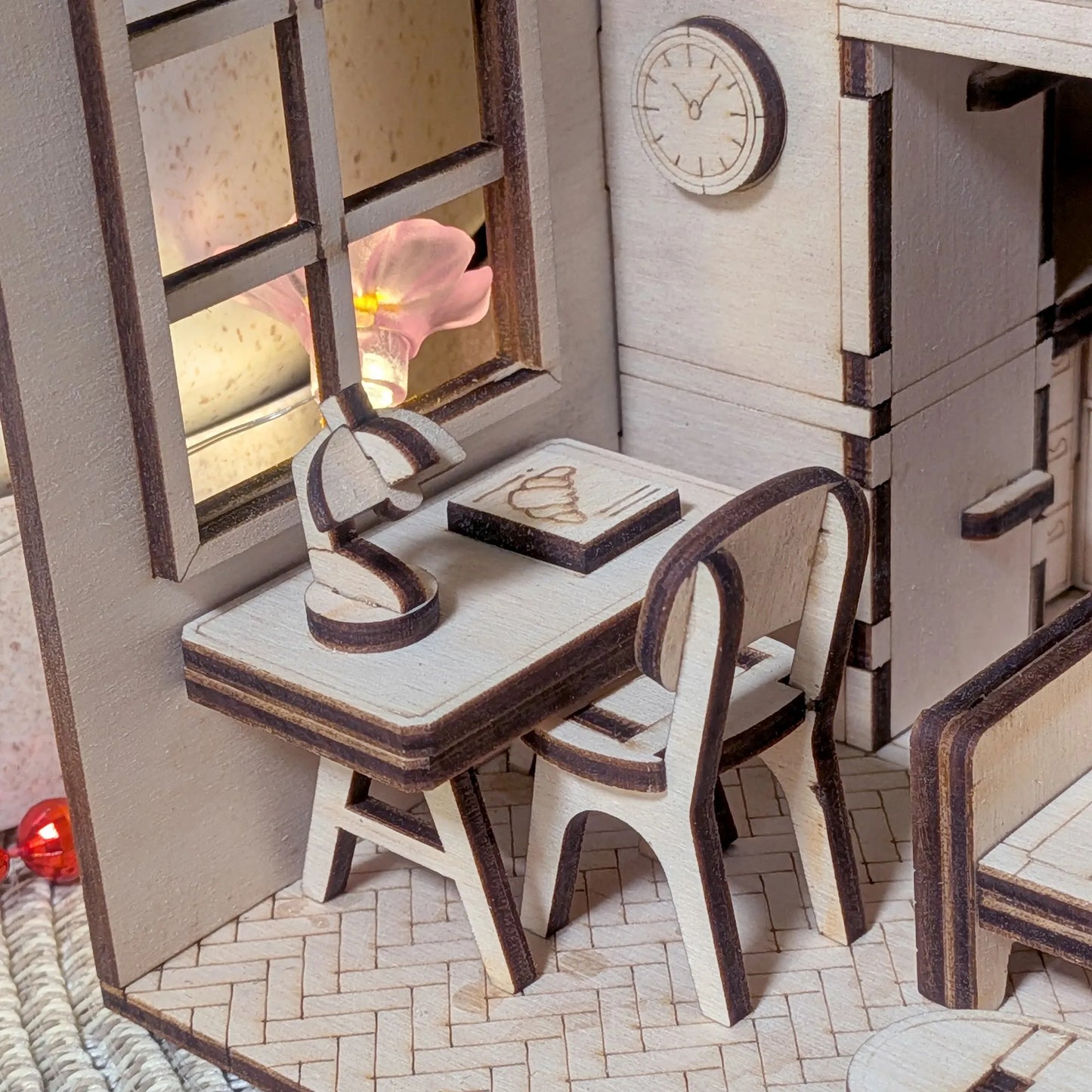 Miniature model of a dining area with table, chairs, and decorative elements.