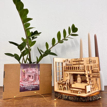 Wooden model of a room with furniture, candles, and a plant on a wooden surface.