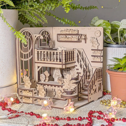 Wooden book nook model with intricate details on a decorative surface with plants and lights.