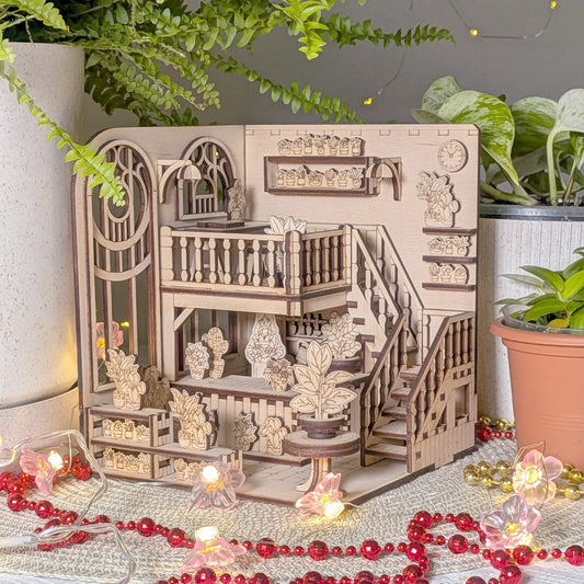 Wooden book nook model with intricate details on a decorative surface with plants and lights.