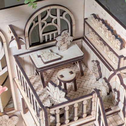Wooden book nook model with furniture and decorative elements.