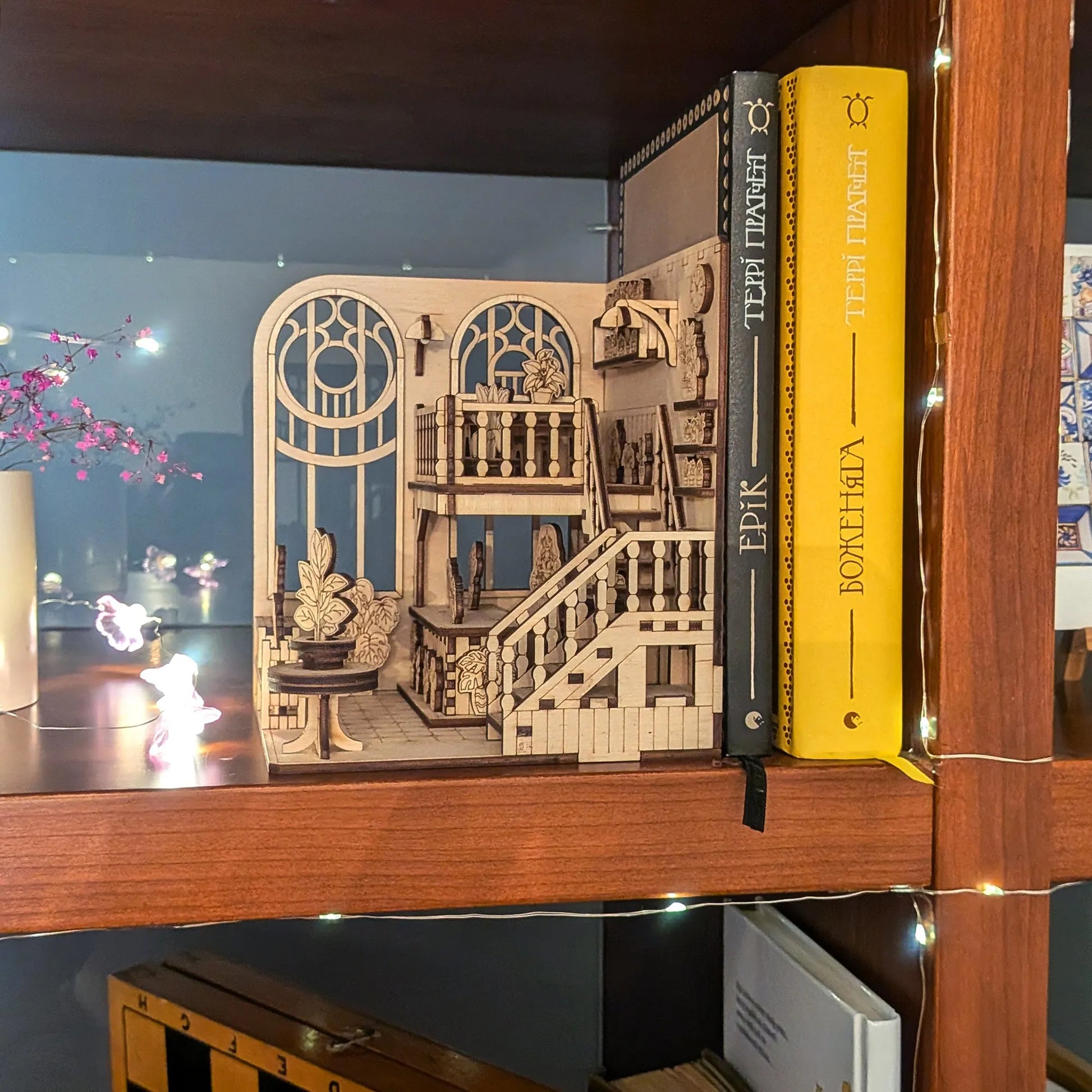 Wooden model of a staircase on a bookshelf with books around