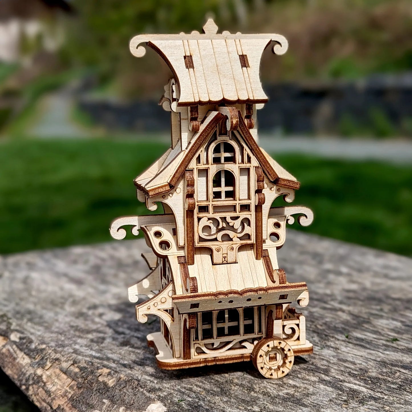 Wooden model of a pagoda-like structure on a stone surface with a blurred natural background