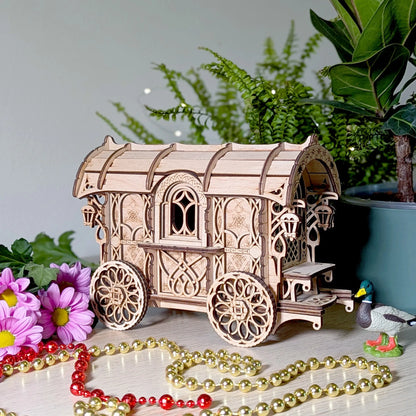 Wooden model of a gypsy caravan with decorative elements on a surface.