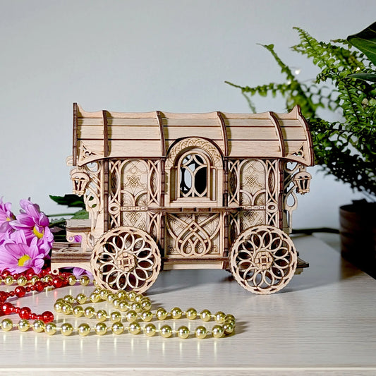 Wooden model of a caravan wagon with intricate designs on a surface with flowers and beads.