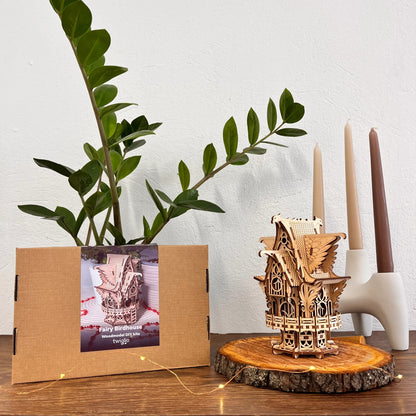 Fairy birdhouse on a wooden base with a plant and candles in the background