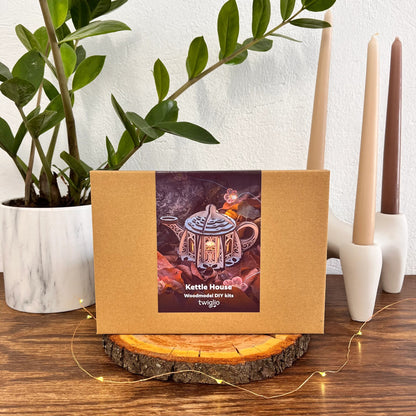 Kettle House wooden light in a decorative box on a wooden surface with candles and plants in the background