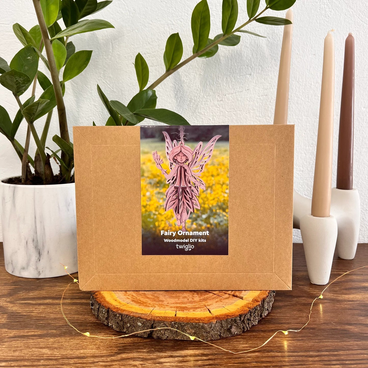 Fairy ornament kit packaging on a wooden surface with plants and candles in the background