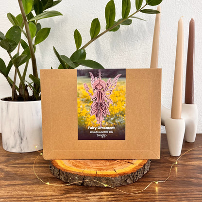 Fairy ornament kit packaging on a wooden surface with plants and candles in the background