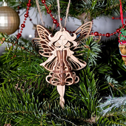 Wooden fairy ornament hanging on a Christmas tree with red beads.