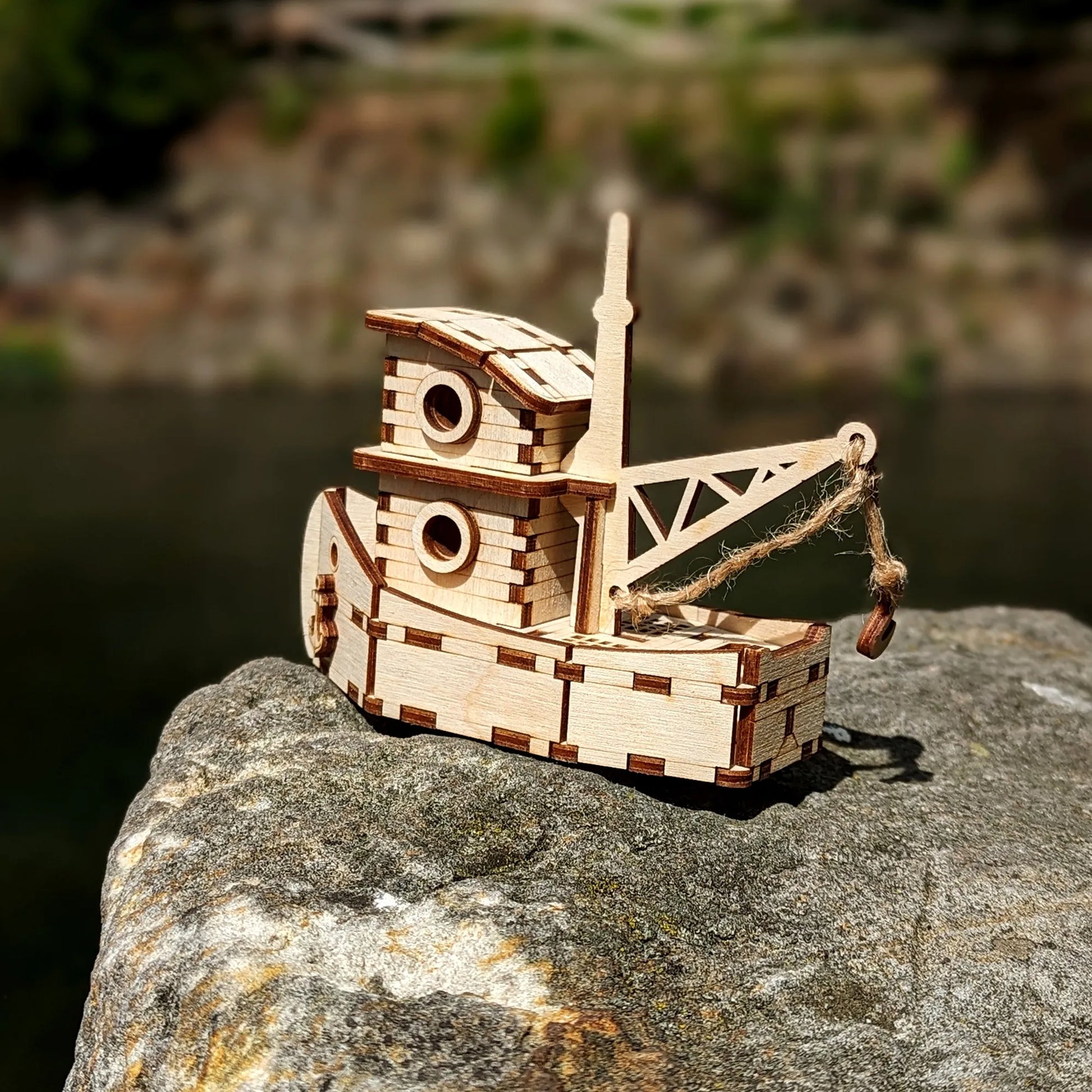 Wooden model of a boat on a rock with a blurred natural background