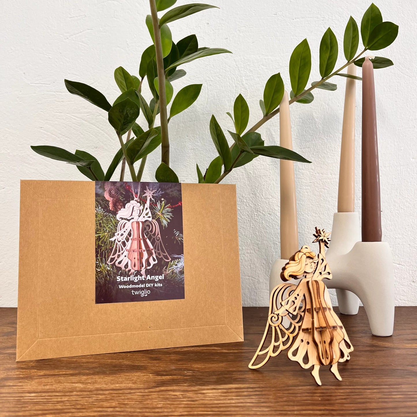 Wooden angel sculpture next to a plant and decorative items on a wooden surface.