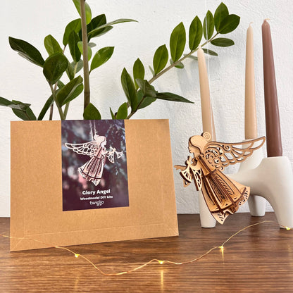 Wooden angel ornament with packaging on a wooden surface with candles and plants.