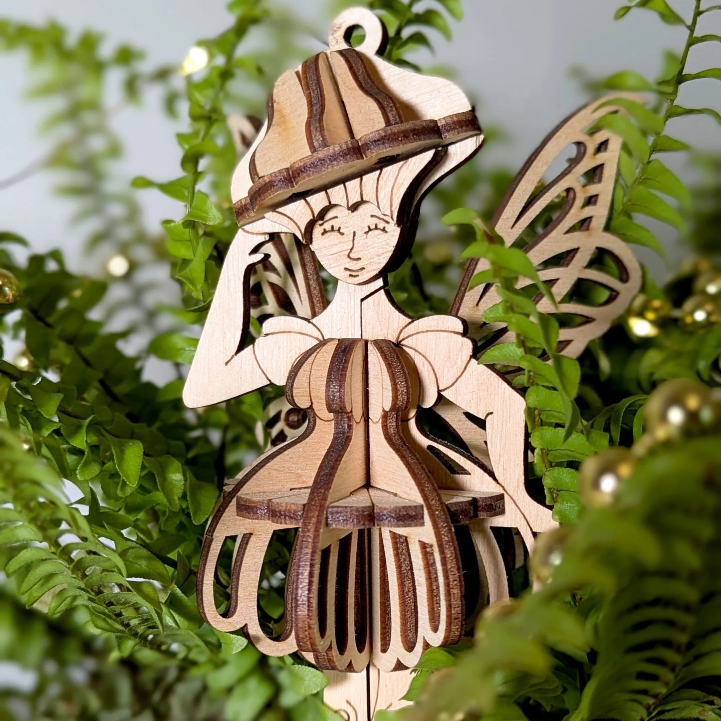 Wooden fairy ornament with a hat and wings on green leaves