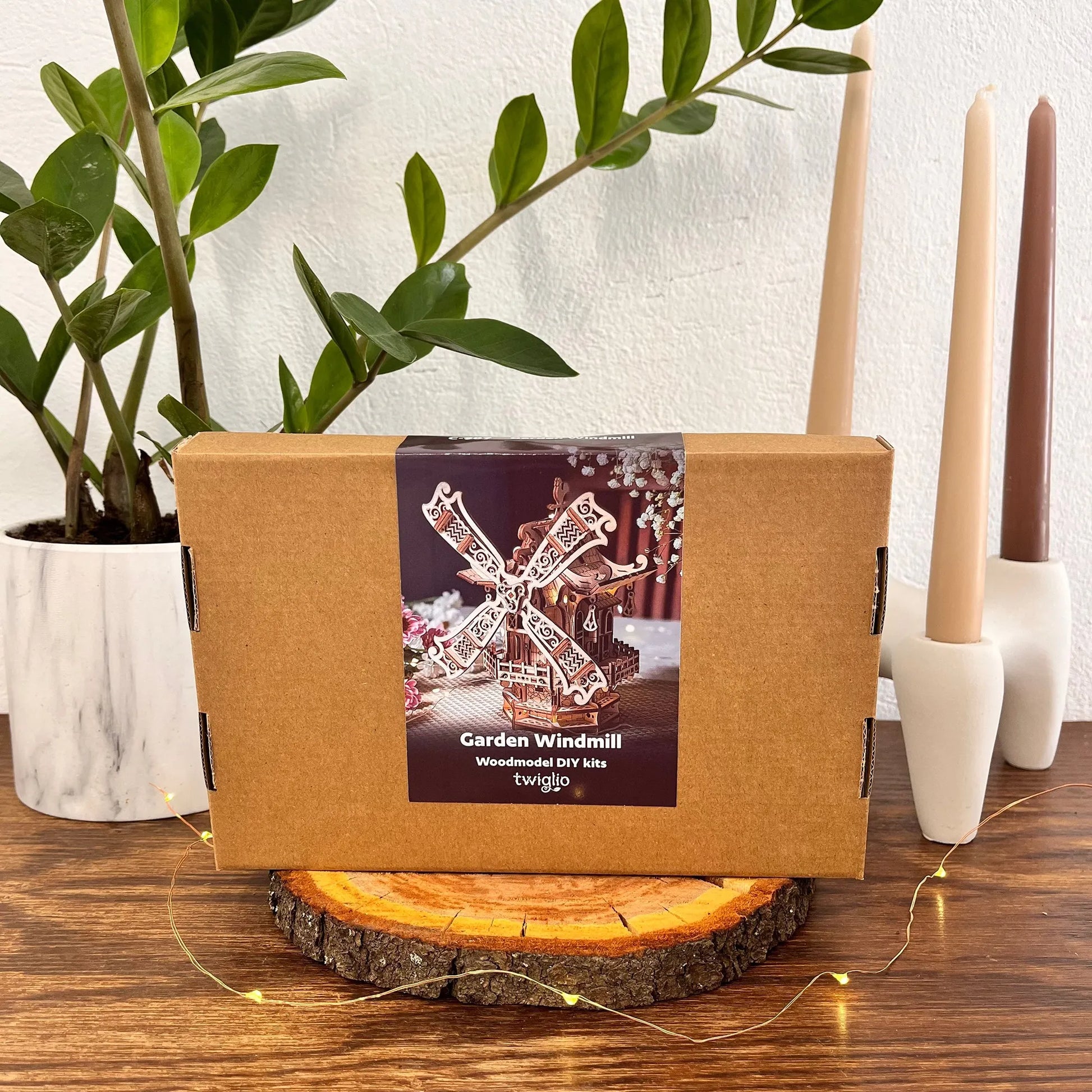 Cardboard box with a windmill design on a wooden surface with candles and a plant.