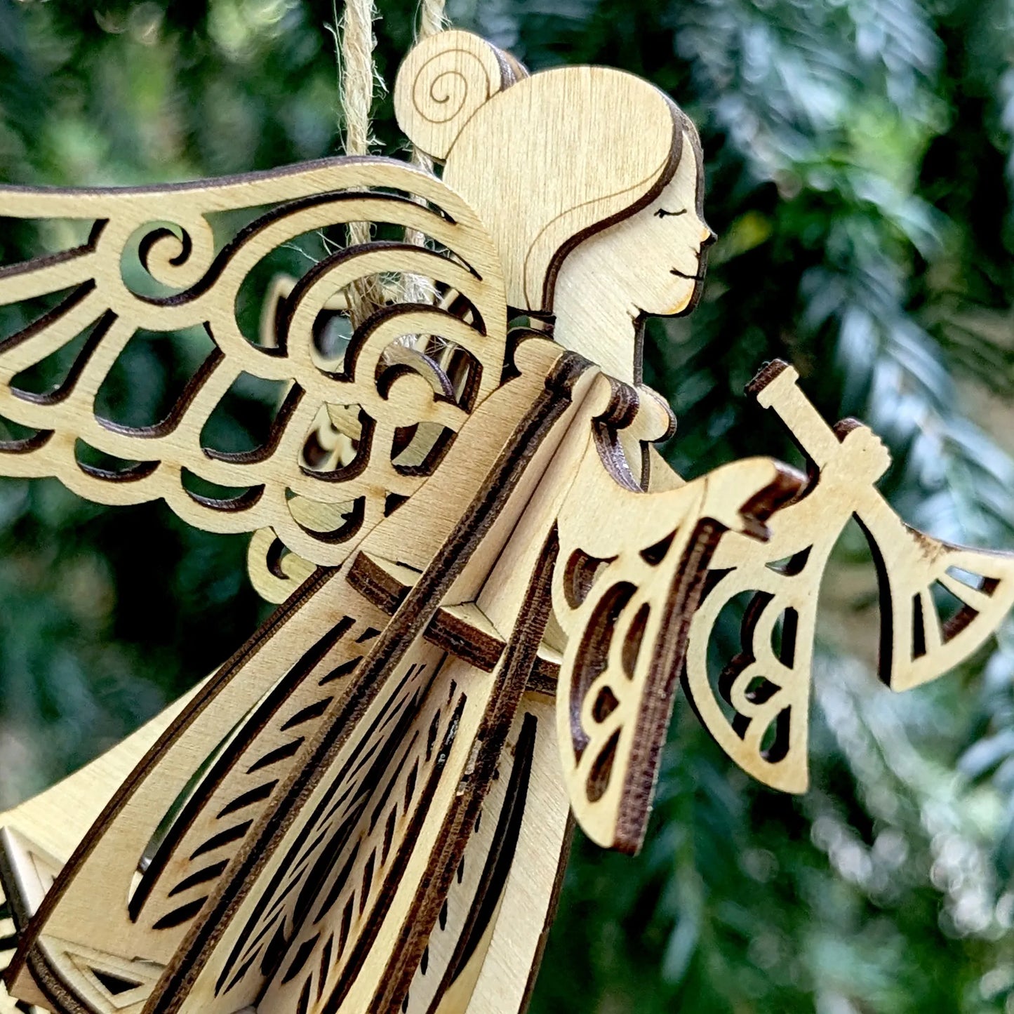 Wooden angel ornament with intricate designs against a blurred green background