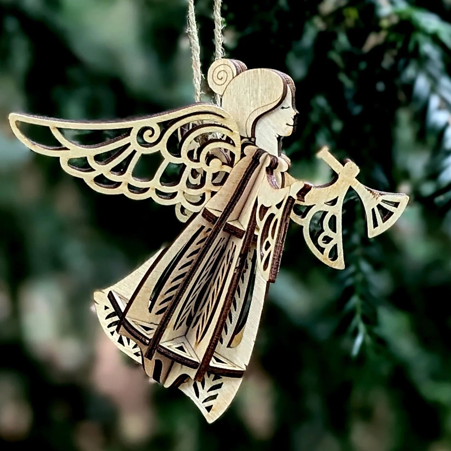 Wooden angel ornament hanging against a green foliage background