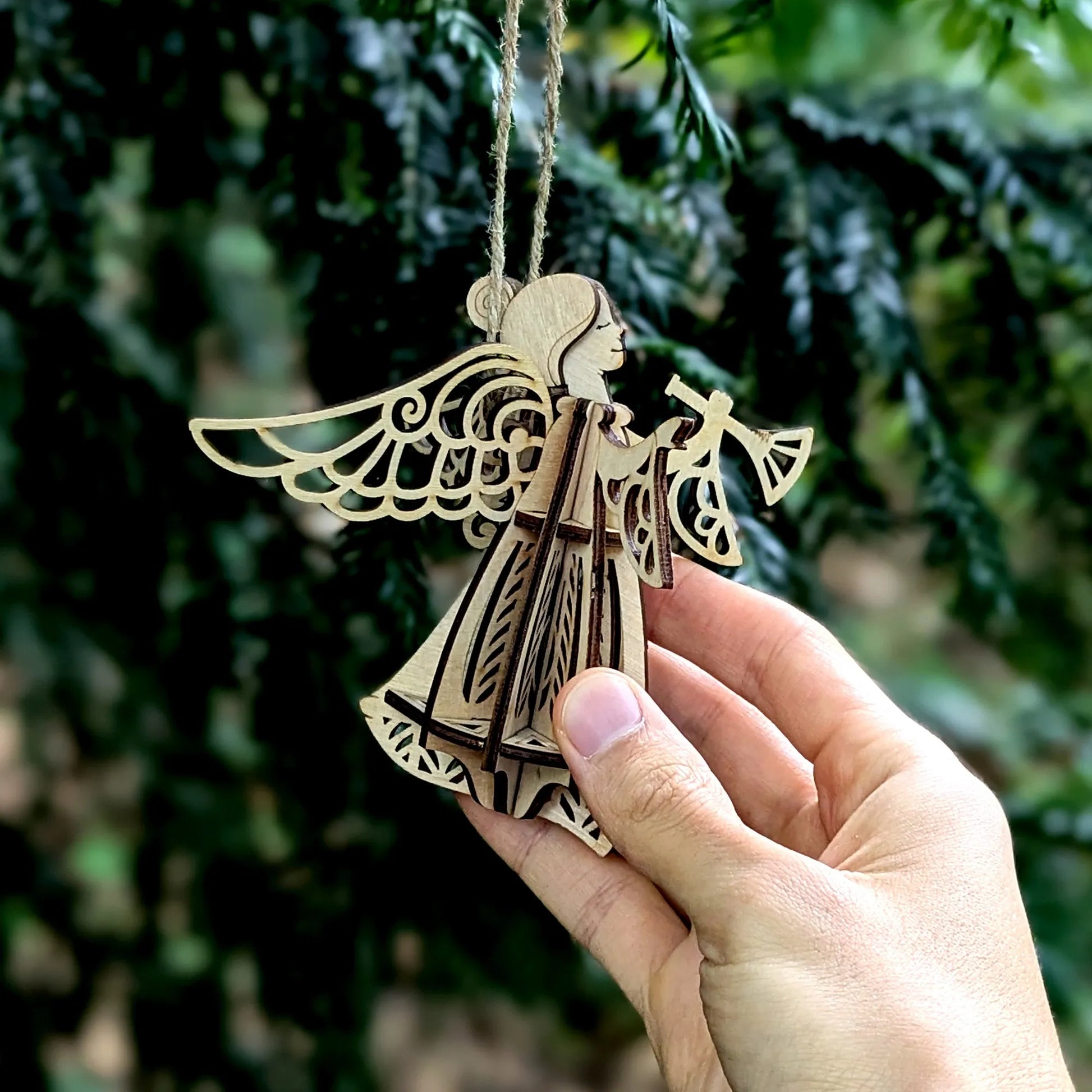 Wooden angel ornament held in a hand with a blurred green background
