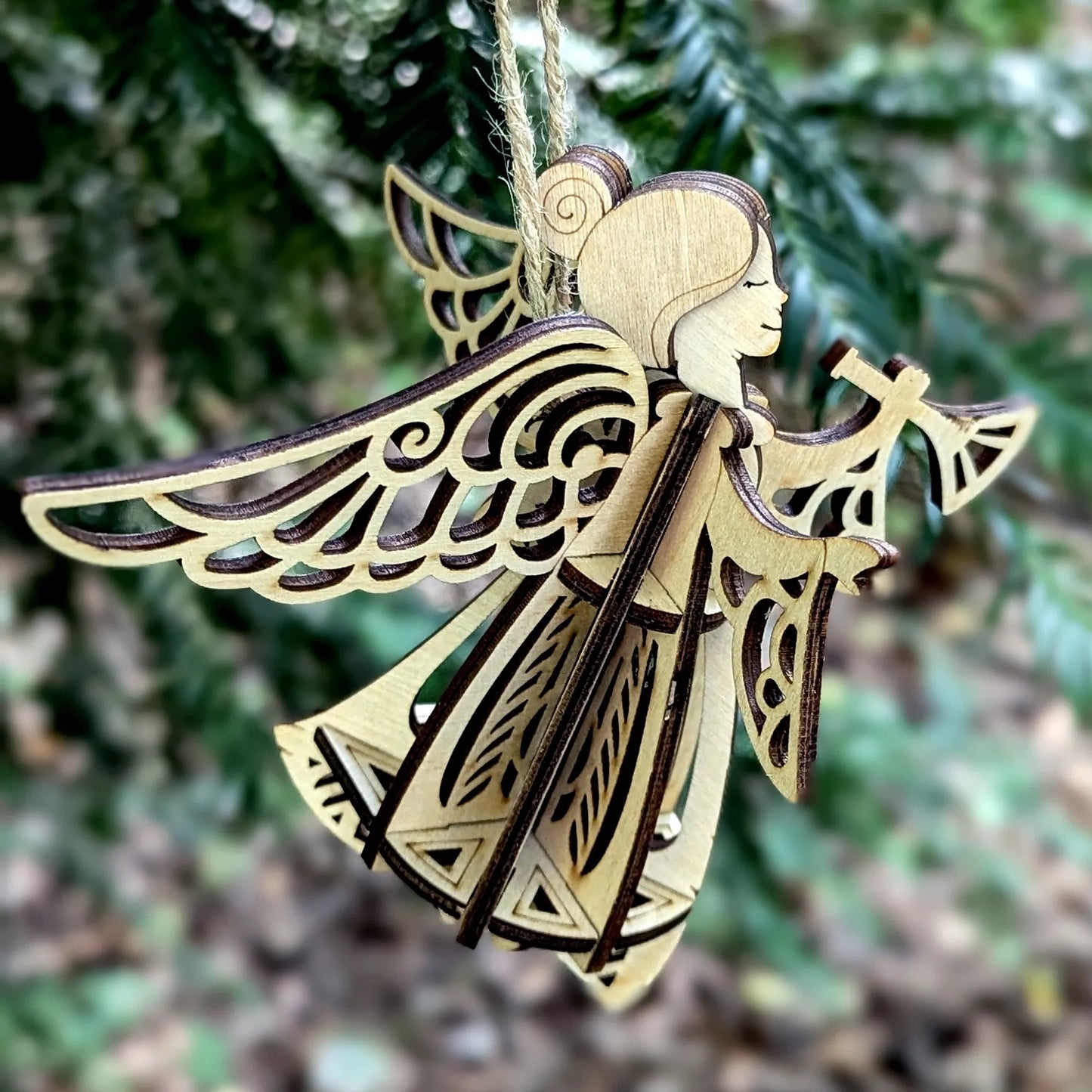 Wooden angel ornament with intricate designs against a blurred green background