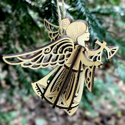 Wooden angel ornament with intricate designs against a blurred green background