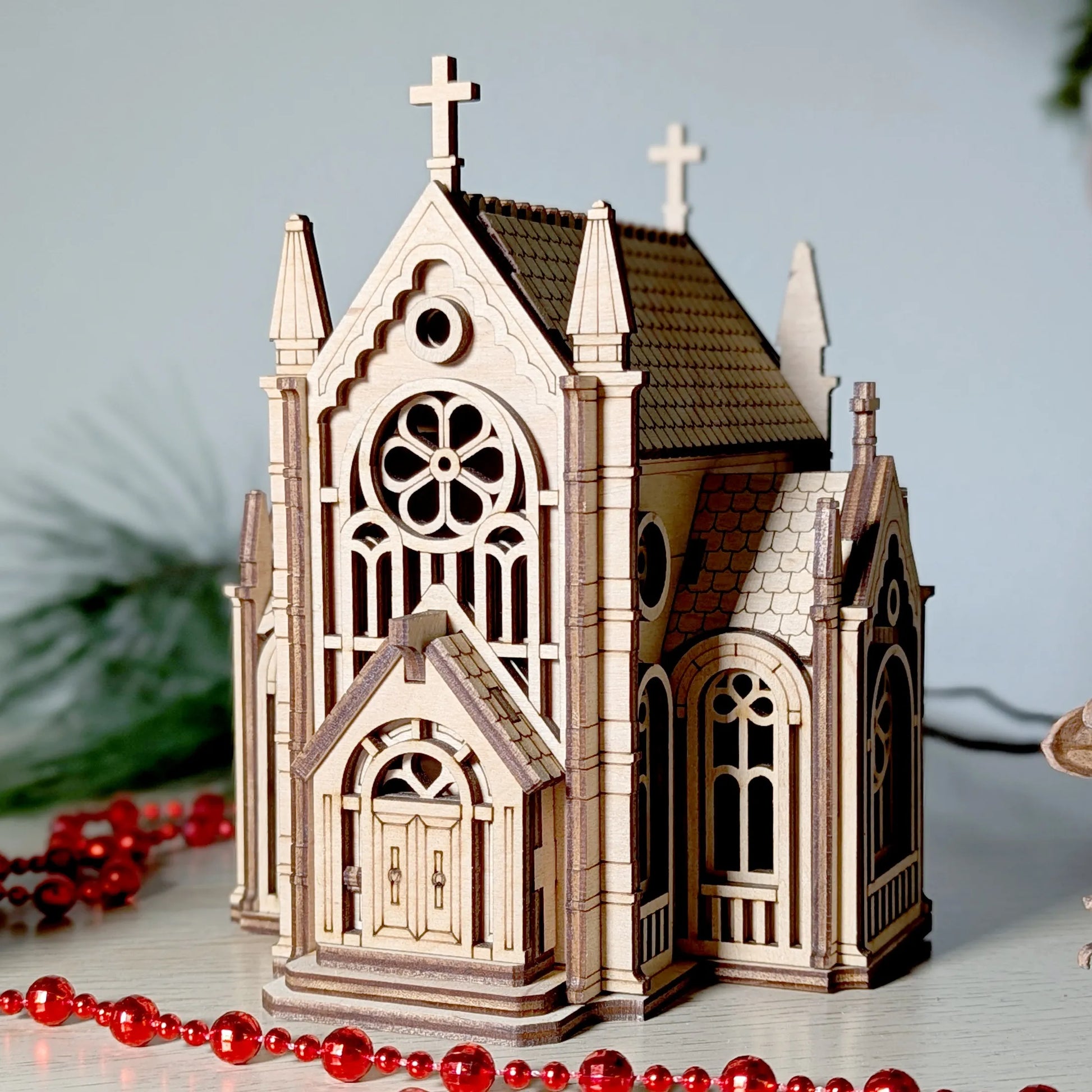 Detailed model of a Gothic-style church with red beads on a light background