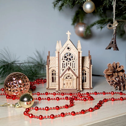 Wooden church ornament with red beads and Christmas decorations on a light surface.